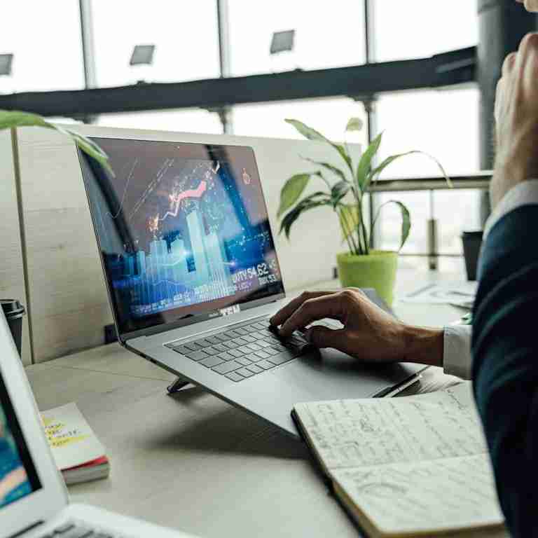 A professional analyzing stock market data on a laptop in a bright office environment.