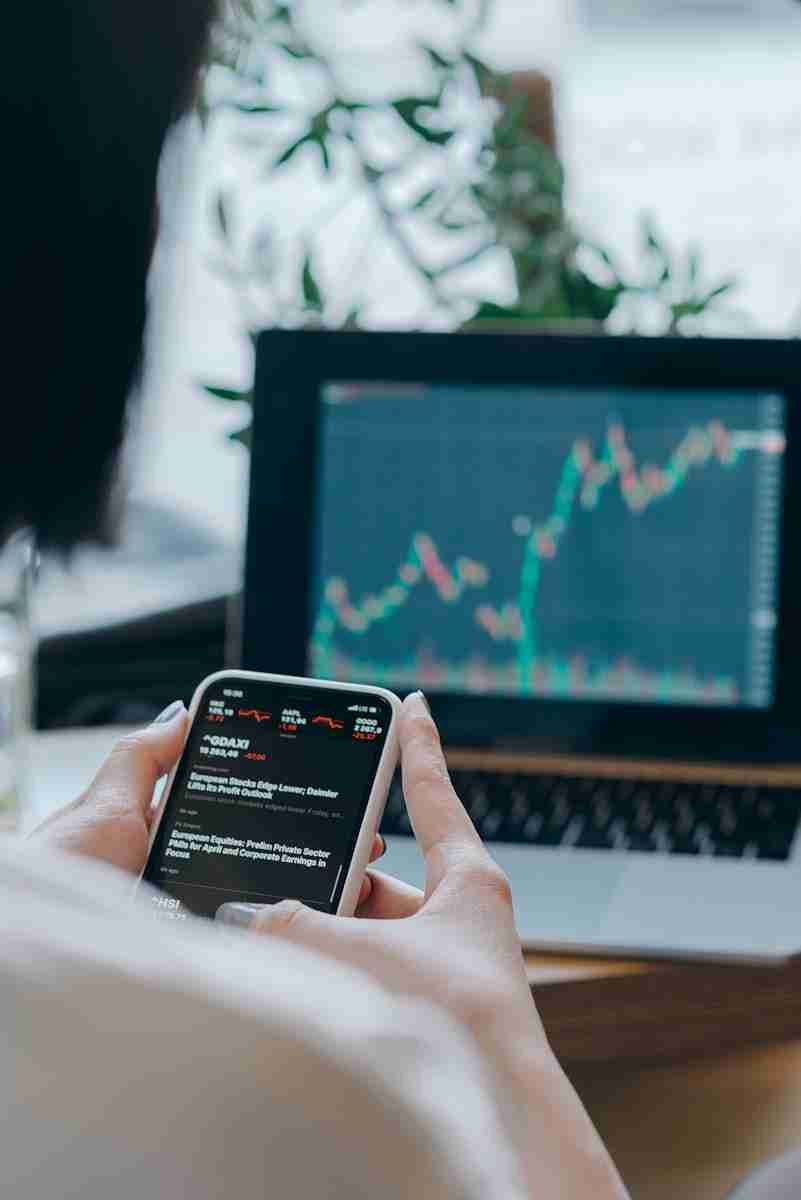 Pricing Person using smartphone for stock market analysis at home office.